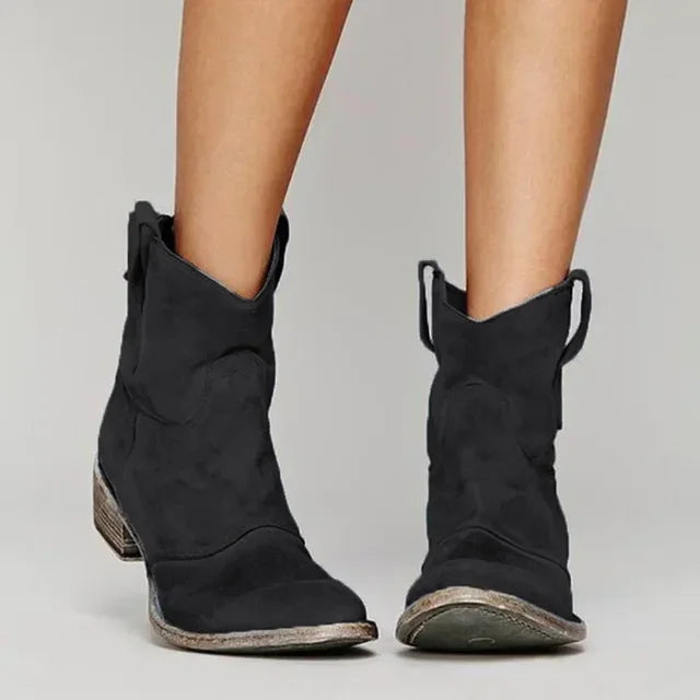 Black ankle boots worn by a person on a plain background