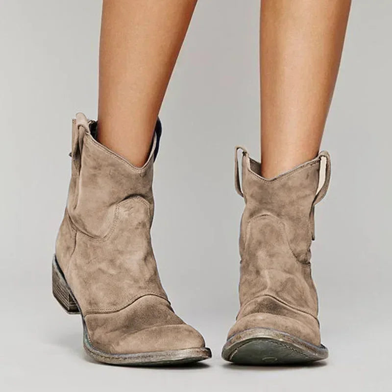 Pair of brown suede cowboy boots on a neutral background