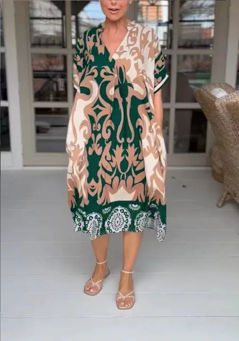 Woman wearing a patterned dress with green accents in an indoor setting.