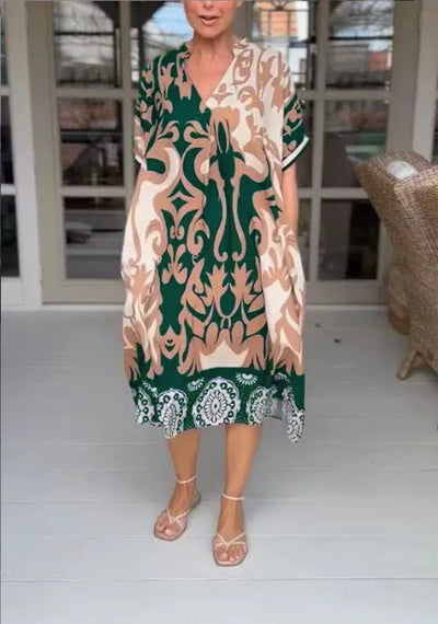 Woman wearing a patterned dress with green accents in an indoor setting.